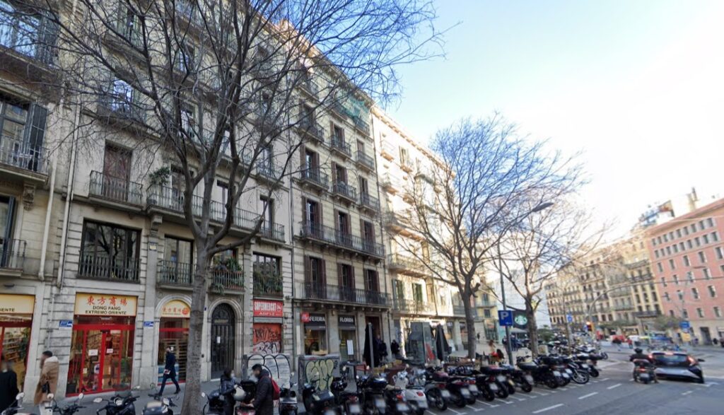 exterior edificio con locales, coches y motos